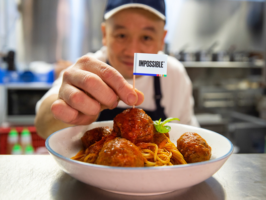 A chef puts an Impossible flag into a plate of Impossible meatballs at Privé Wheelock in Singapore.