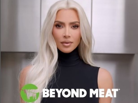 Kim Kardashian with blonde hair wearing a black mock turtleneck