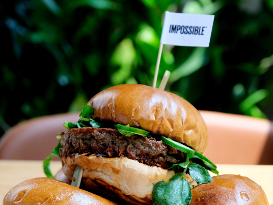Stack of Impossible Burgers topped with a flag that reads "Impossible"