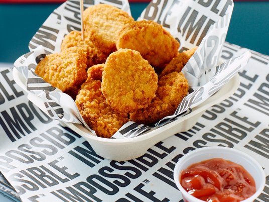 Impossible chicken nuggets served in a paper container with a small plastic container of ketchup