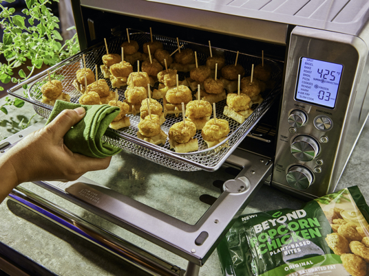 Tray of Beyond Meat popcorn chicken coming out of a toaster oven.